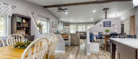 A spacious kitchen with a dining area, wooden flooring, and a ceiling fan.
