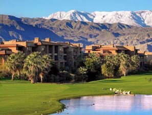 Een resort met meerdere gebouwen, een golfbaan en een berg op de achtergrond.