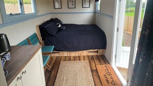 L’intérieur chaleureux d’un chalet comprend un lit, une petite kitchenette et une fenêtre donnant sur un jardin.
