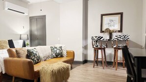 A modern living room with a sofa, a coffee table, a dining table with zebra-patterned chairs, and a framed artwork on the wall. - Suite Home Indiana #2 (Evansville)