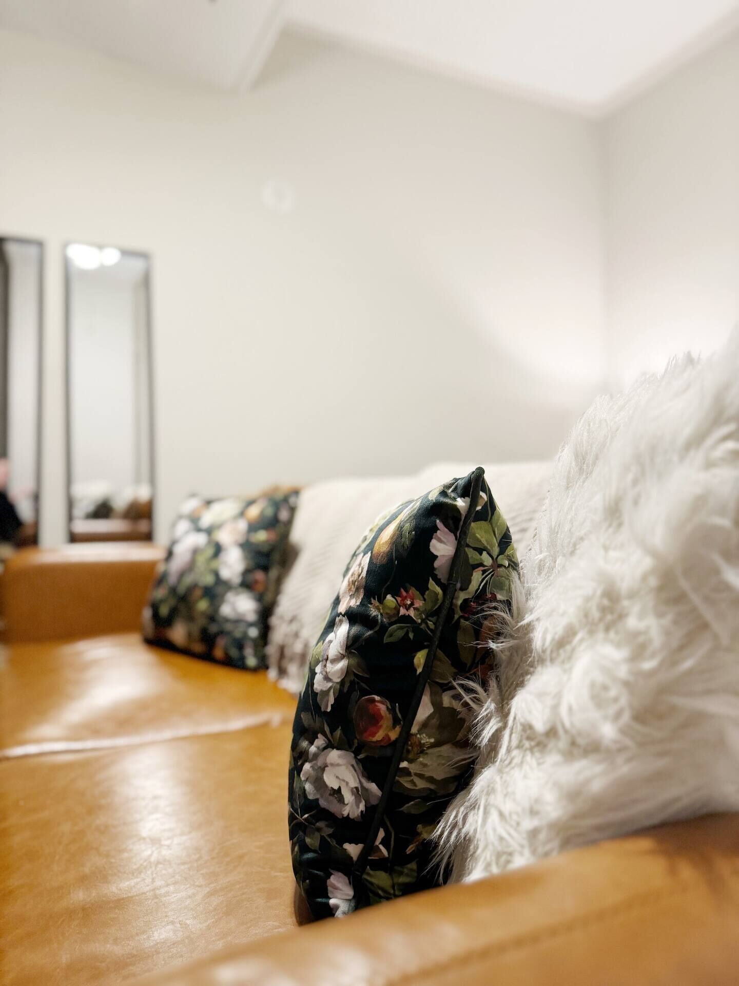 Un lit avec un coussin à motifs floraux et une couverture blanche et moelleuse.