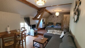 A cozy loft-style living space with a dining area, a sofa, and a TV. - Gîte Grande Capacité in Champagne (Verdon)