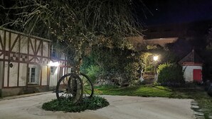 A courtyard with a large wheel sculpture, a traditional building with exposed timber framing, and a small red-roofed structure. - Gîte Grande Capacité in Champagne (Verdon)