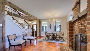 A spacious living area with a wooden staircase, a fireplace, and a dining table with chairs. - The Tannery  
A swanky, eclectic and fun adult retreat. (Lancaster)