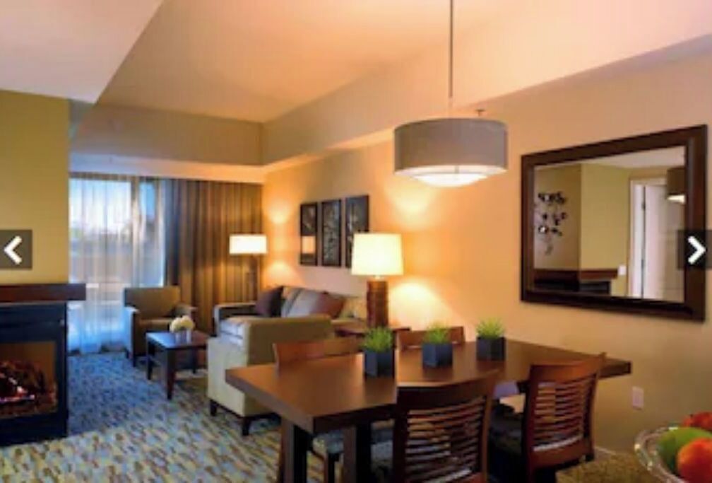 Une chambre d’hôtel avec un coin repas, une cheminée et un grand miroir au mur.