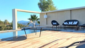 An outdoor pool area with a wooden deck, two lounge chairs, and a table. - T3 apartement adjoining a luxury villa, 6 people, 70m2 (La Roquette-sur-Siagne)
