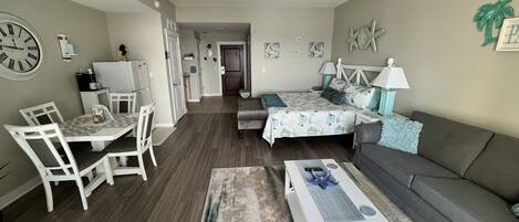 Un espacio habitable compacto con comedor, sofá, cama y una pequeña kitchenette.