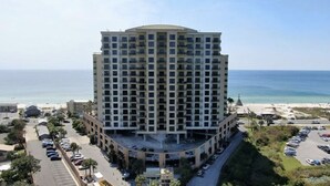Un hôtel de grande hauteur doté d’une cour intérieure, situé près d’une plage et offrant une vue sur l’océan, avec un parking à proximité.