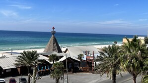 Un bâtiment situé au bord de la plage, doté d’un toit conique et d’une enseigne, entouré de palmiers et offrant une vue sur l’océan.