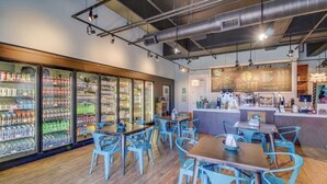 Un café avec des tables, un comptoir et des présentoirs réfrigérés pour les boissons.