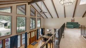 A spacious loft with large windows, a dining area, a staircase, and a green couch. - Huge Mountain Chalet - Gourmet Chefs Kitchen - Pool - One Block From Sandy River (Rhododendron)