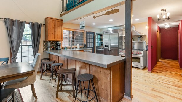 A modern kitchen with a central island, bar stools, and a dining area with a table and chairs. - Huge Mountain Chalet - Gourmet Chefs Kitchen - Pool - One Block From Sandy River (Rhododendron)