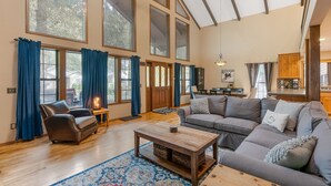 A spacious living room with large windows, a fireplace, and a cozy seating area. - Huge Mountain Chalet - Gourmet Chefs Kitchen - Pool - One Block From Sandy River (Rhododendron)