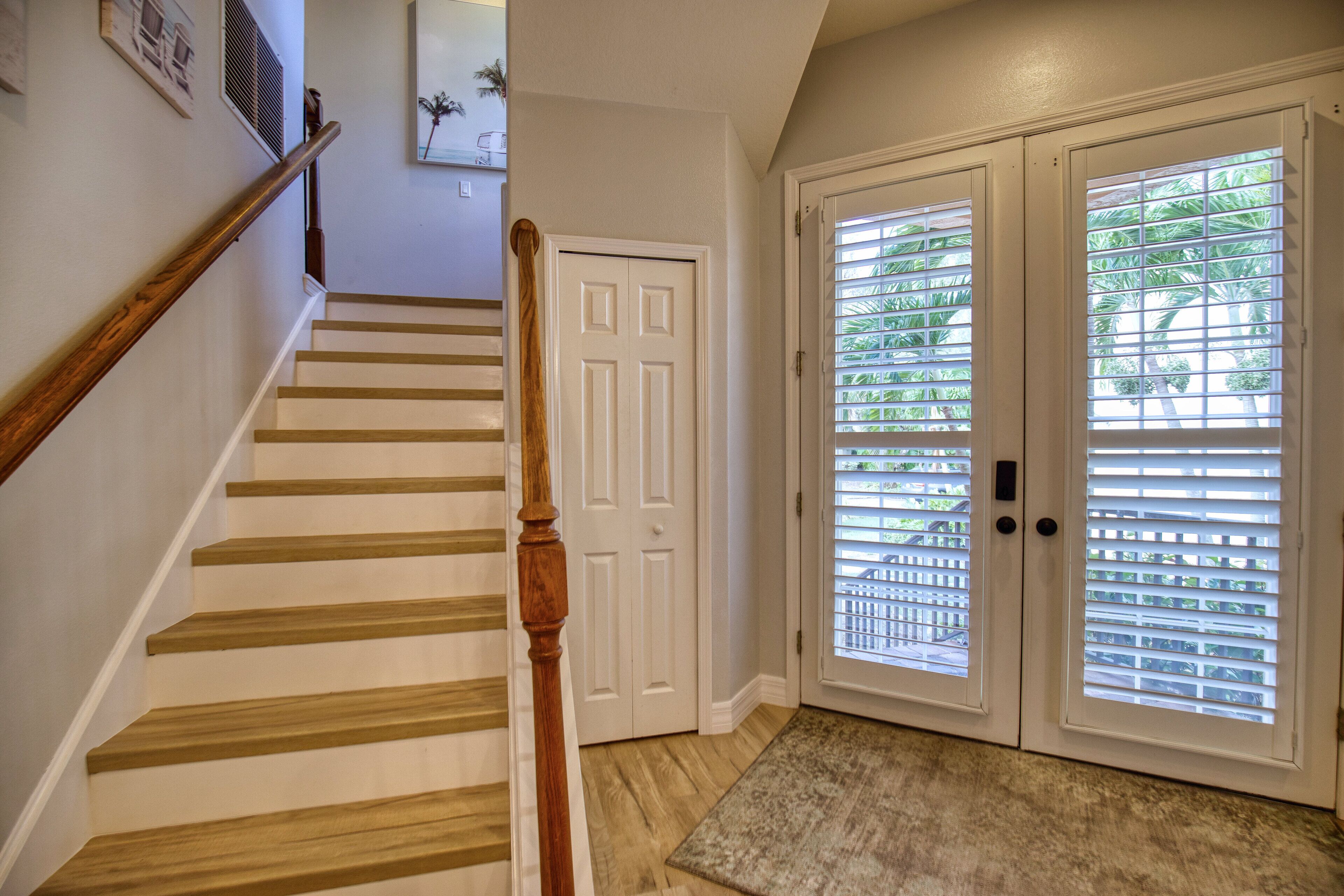 A staircase with wooden steps and a wooden handrail, leading to a white door with a doorknob.