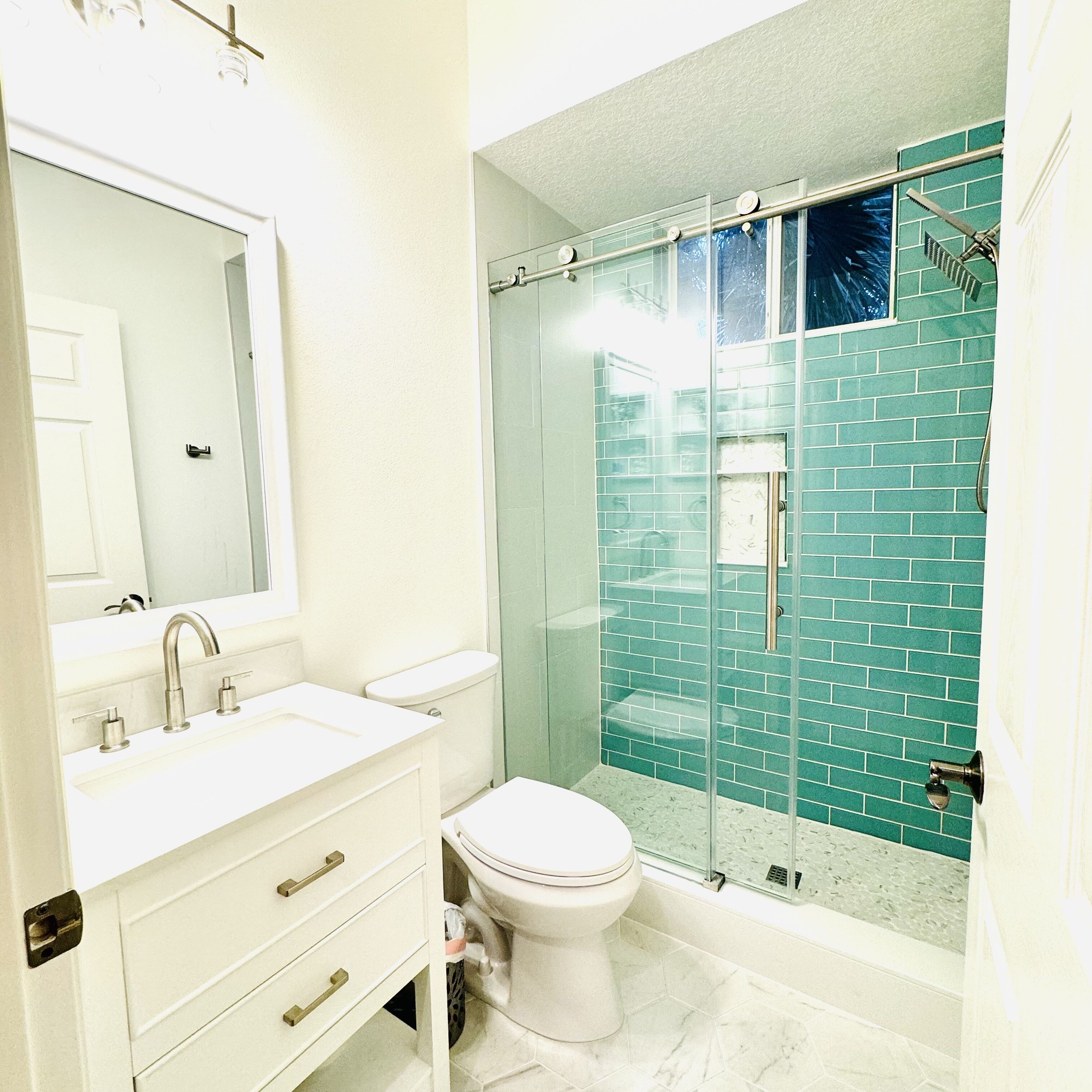 A bathroom with a white sink, a toilet, and a glass-enclosed shower area.