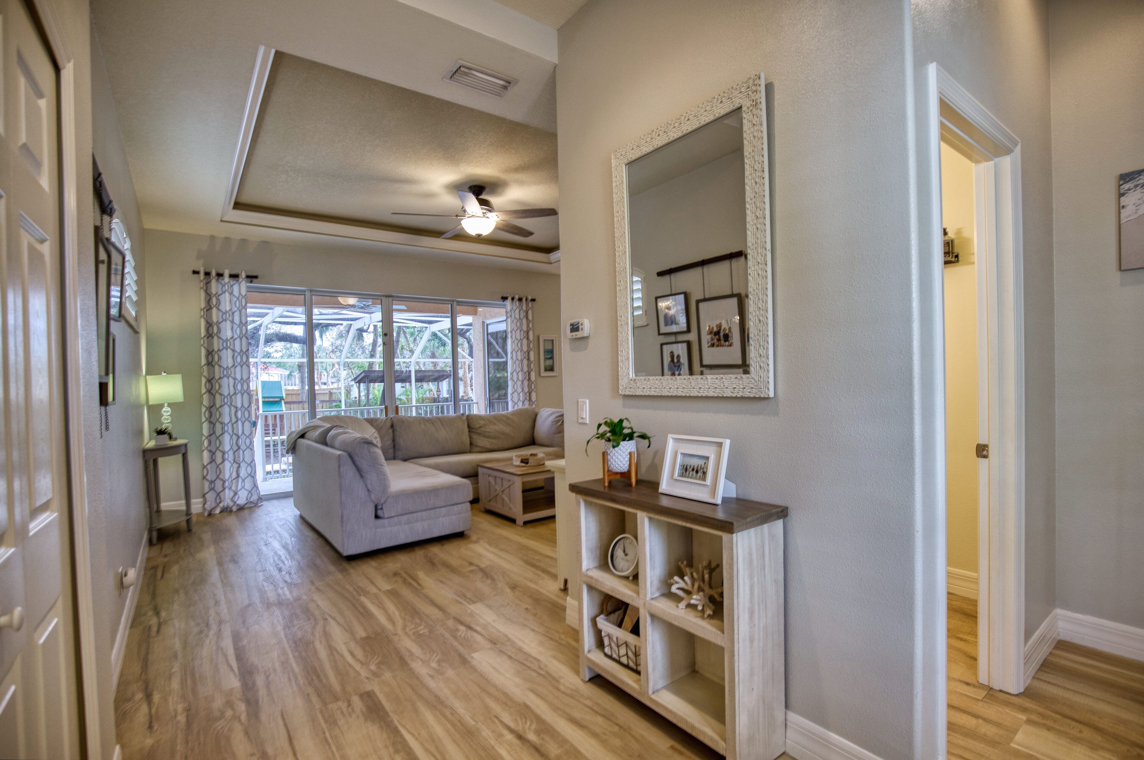 A spacious living room with a grey sofa, a wooden coffee table, and a ceiling fan.