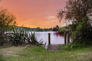 Un muelle de madera que conduce a un lago tranquilo bajo un cielo al atardecer.