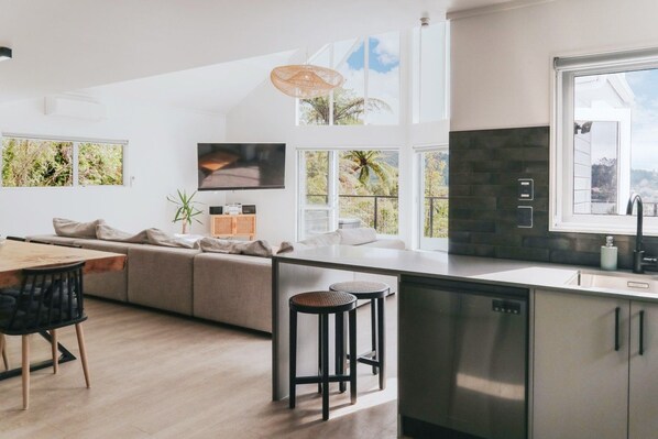 Open-plan living, dining and kitchen with bush and lake outlook