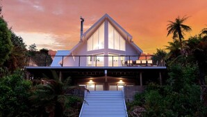Una casa moderna con techo triangular, un balcón y una escalera que lleva a la entrada.