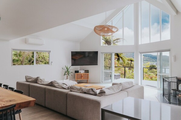 Living area with dining table and kitchen bench - Architectural Lakehouse | Panoramic Views | Boat Mooring | Space for 14 (Okere Falls)