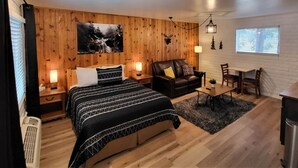 A cozy bedroom with a bed, a sofa, a dining table, and a fireplace. - The Nook Pinetop (Pinetop)