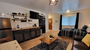 A compact living space with a kitchenette, a sofa, a coffee table, and a TV. - The Nook Pinetop (Pinetop)