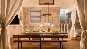 A dining area with a wooden table, benches, and hanging light fixtures.