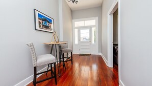 A hallway with wooden flooring, a white door, and a framed picture on the wall.