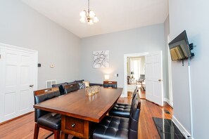 A dining room with a large wooden table, black leather chairs, and a chandelier.