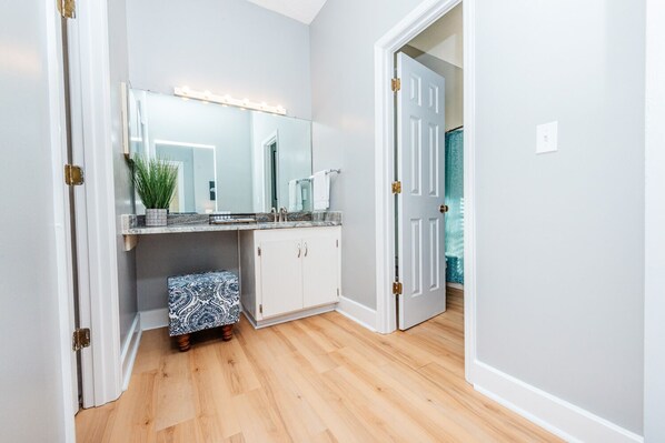 A bathroom with a vanity, mirror, and lighted vanity lights.