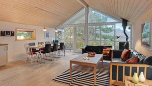 A spacious living area with a high ceiling, large windows, a dining table with chairs, and a sofa. - 3 bedroom lovely home in Ebeltoft (Ebeltoft)