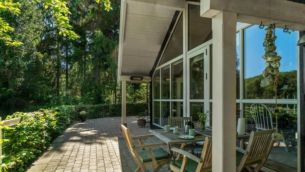 A covered outdoor seating area with a brick floor, wooden chairs, and a table with a teapot and cups. - 3 bedroom lovely home in Ebeltoft (Ebeltoft)