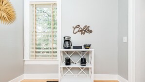 A white console table with a coffee maker, a blender, and a mug on top. A 'Coffee' sign is on the wall. - Downtown Macon Duplex-Walk to Concerts, Food & Nightlife (Macon)