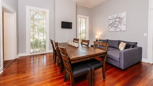 A dining area with a wooden table, chairs, and a grey sofa. - Downtown Macon Duplex-Walk to Concerts, Food & Nightlife (Macon)