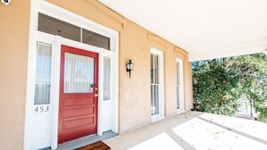 A beige building with a red door, white shutters, and a welcome mat. - Downtown Macon Duplex-Walk to Concerts, Food & Nightlife (Macon)