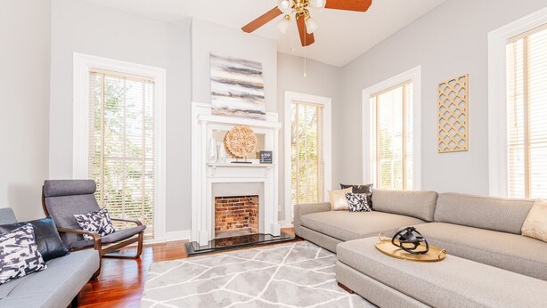 A living room with a fireplace, a ceiling fan, and a large window. - Downtown Macon Duplex-Walk to Concerts, Food & Nightlife (Macon)
