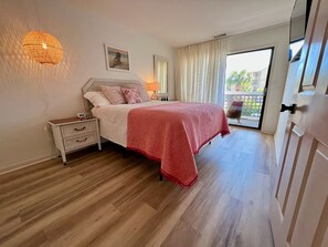 Een slaapkamer met een bed, nachtkastje, lamp en uitzicht op het omliggende landschap.