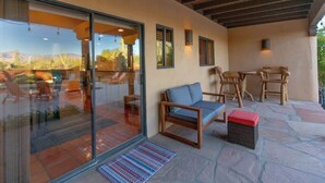 A patio area with a glass door leading to a pool, outdoor seating, and a stone floor. - Spectacular Views, Heated Pool, & Outdoor BBQ (Tucson)