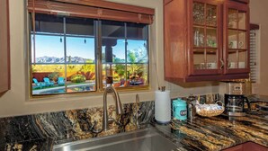 A kitchen with a large window, a sink, and wooden cabinets. - Spectacular Views, Heated Pool, & Outdoor BBQ (Tucson)