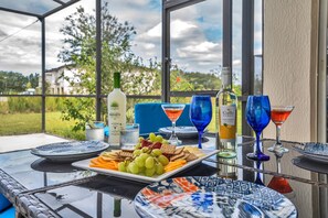 Une table à plateau en verre sur laquelle se trouvent une assiette de collations, une bouteille de vin Gallo Family et deux verres à vin bleus.