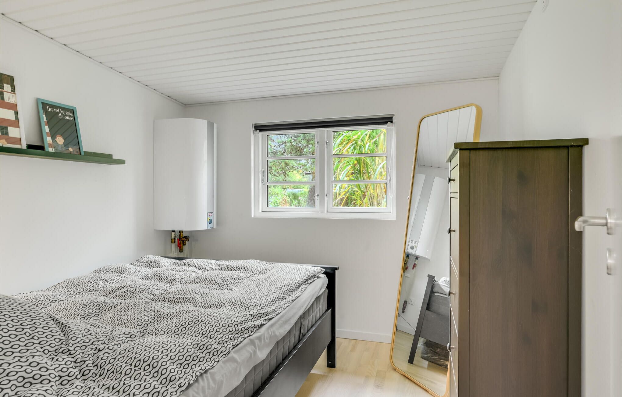 A bedroom with a bed, a window, a wardrobe, and a radiator.