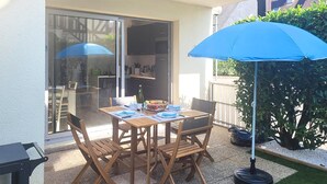 An outdoor patio with a table set for two, surrounded by wooden chairs, and a blue umbrella providing shade. - 1 bedroom stunning apartment in Cabourg (Cabourg)