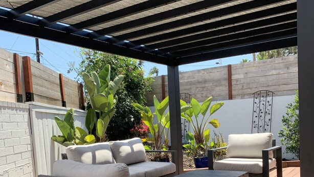 A covered outdoor patio with a sofa, a coffee table, and potted plants. - Sweet cottage home close to beaches, airport and other attractions (San Diego)