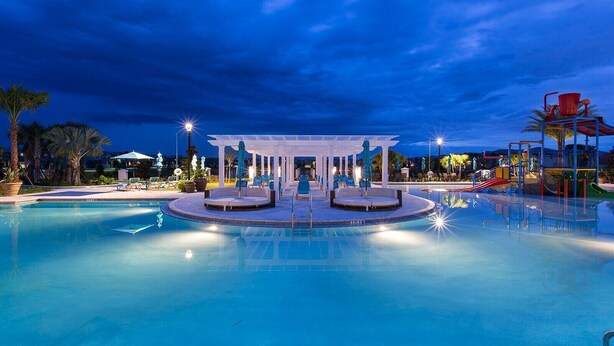 A swimming pool with a central seating area and a children's play structure.