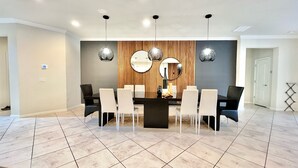 A modern dining area with a rectangular table, six chairs, and three pendant lights.