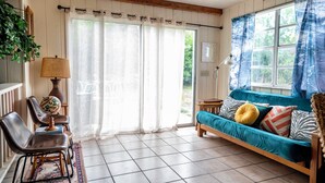Un salon chaleureux avec un canapé bleu, des poutres en bois, un globe terrestre posé sur une table et une vue par une fenêtre ornée de rideaux.
