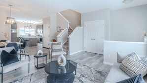 Un salon moderne avec un coin repas, un escalier et une cuisine en arrière-plan.