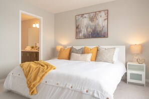 Une chambre à coucher avec un grand lit, une table de chevet avec une lampe, une commode et un miroir.