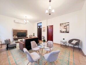 A modern living room with a TV, seating, a glass table, and decorative items.