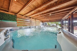 A wooden ceiling, a hot tub, and a wall with greenery.